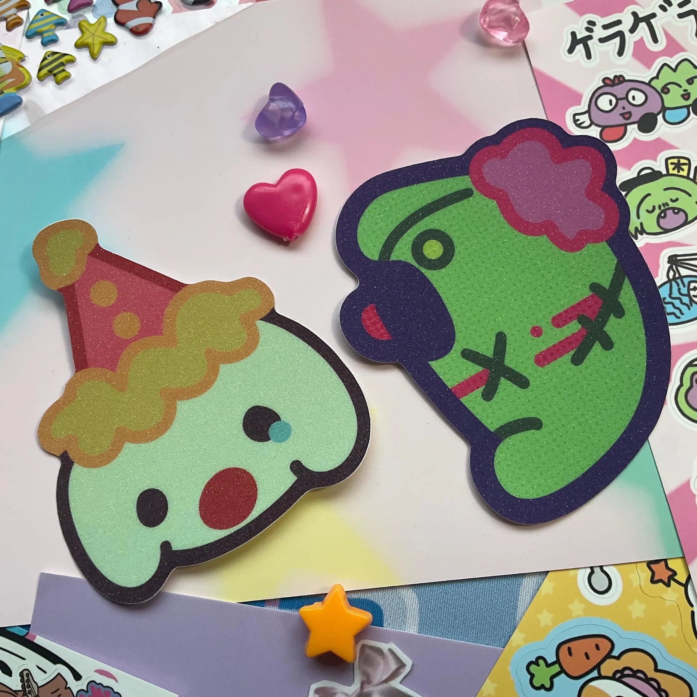 Zombie and clown dog stickers in dog head shape, one green with pink puff on head and one with clown hat, tear and red nose held on paper background